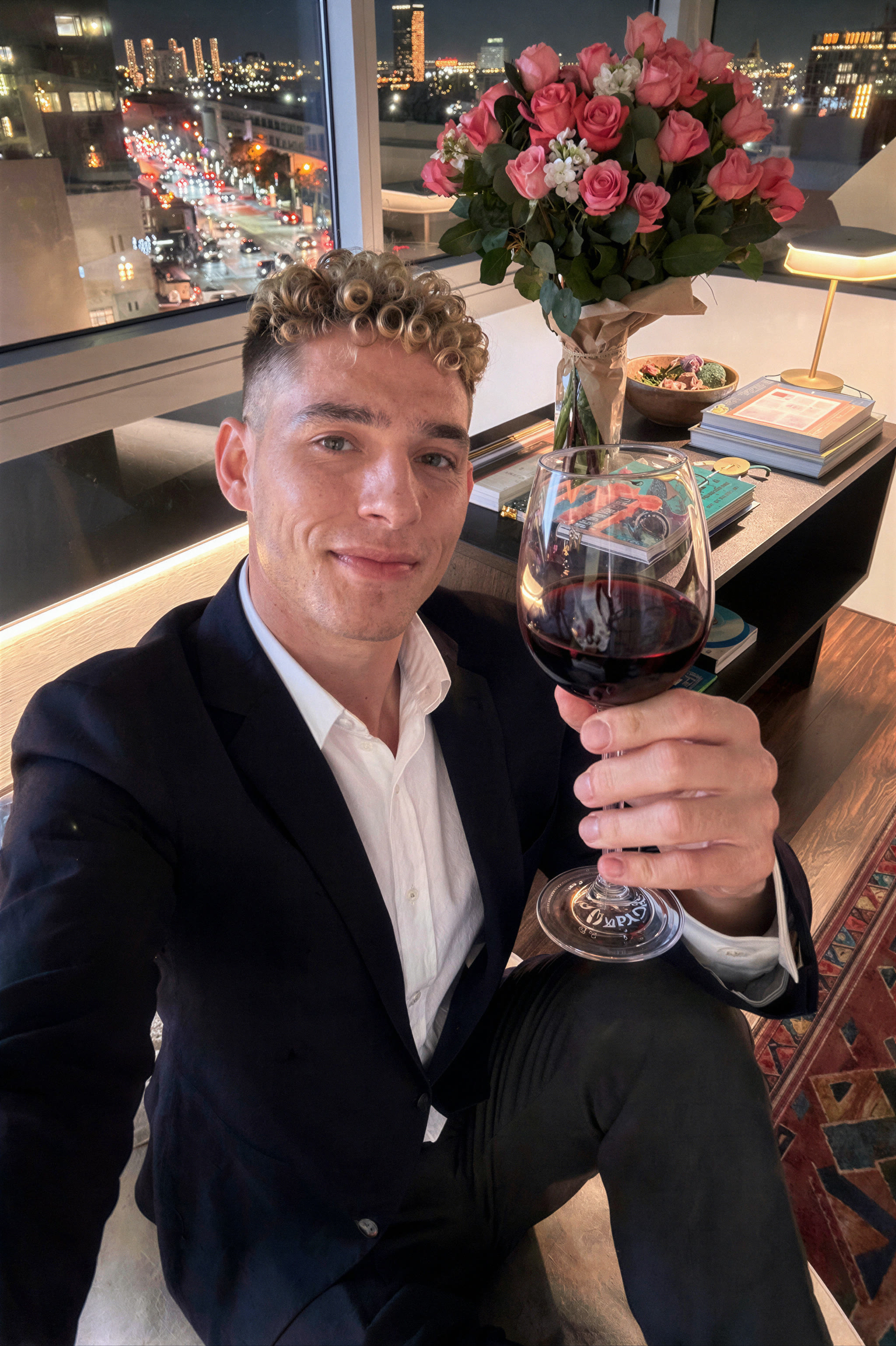 wezoq25 — portrait of wezoq25 raising a glass of red wine by a night-city window
